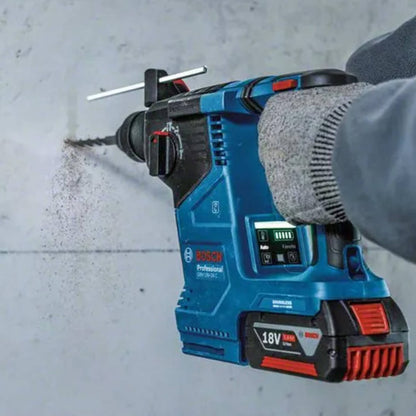 Tradesman using a rotary hammer drill on a concrete wall close up