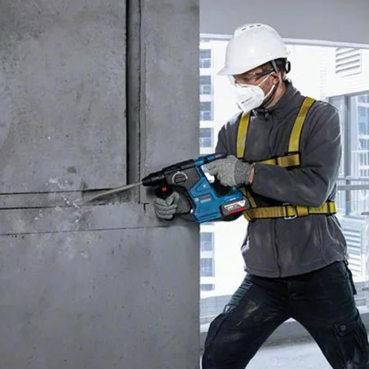 Person using a rotary hammer drill on a concrete wall