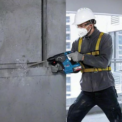 Person using a rotary hammer drill on a concrete wall