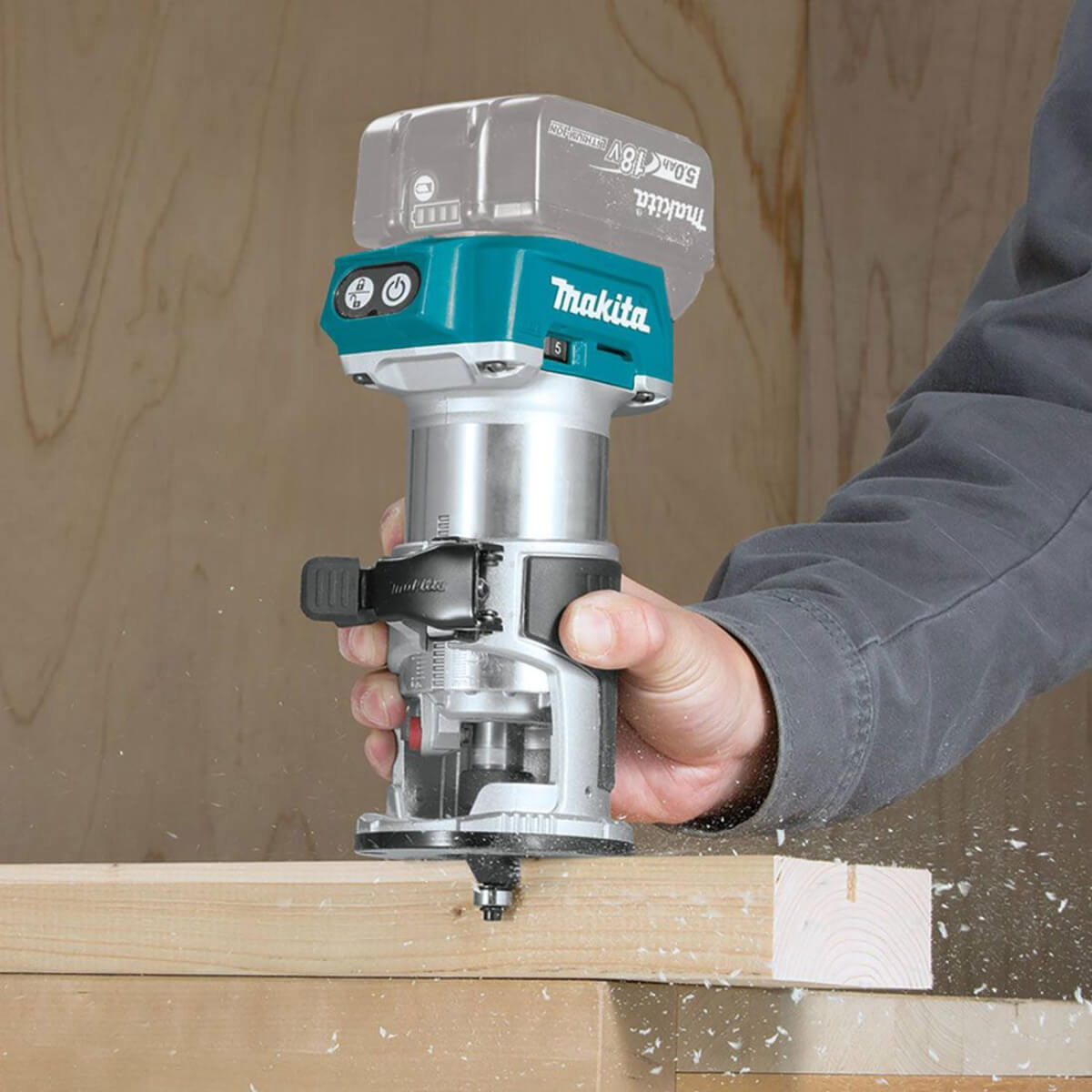 Makita cordless router being used on a piece of wood with a blurred background