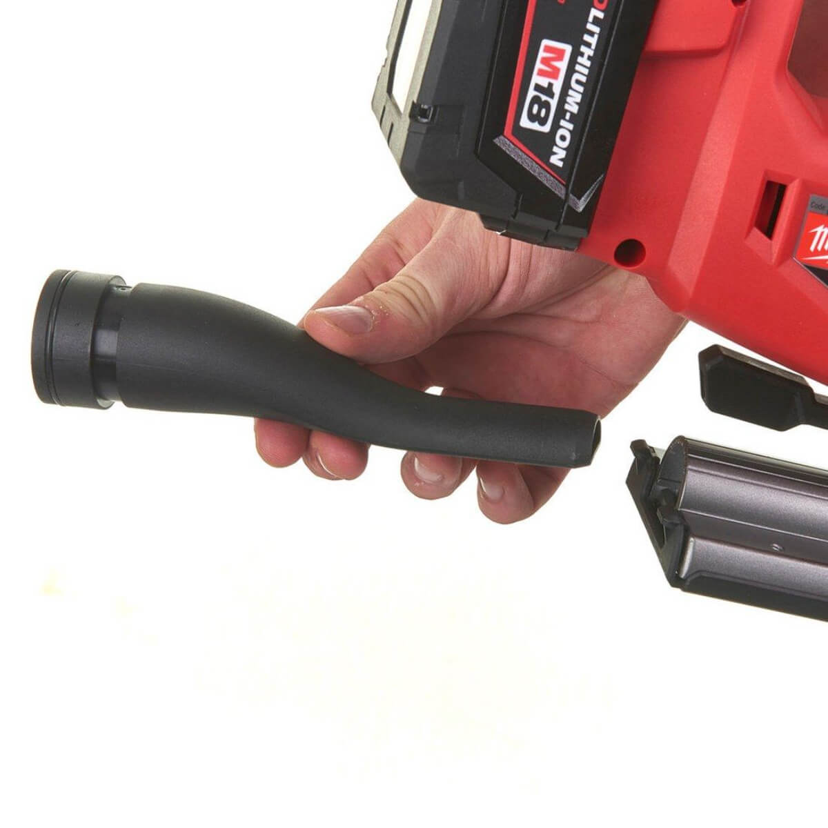 Hand holding a red Jigsaw with a black extraction nozzle attachment on a white background